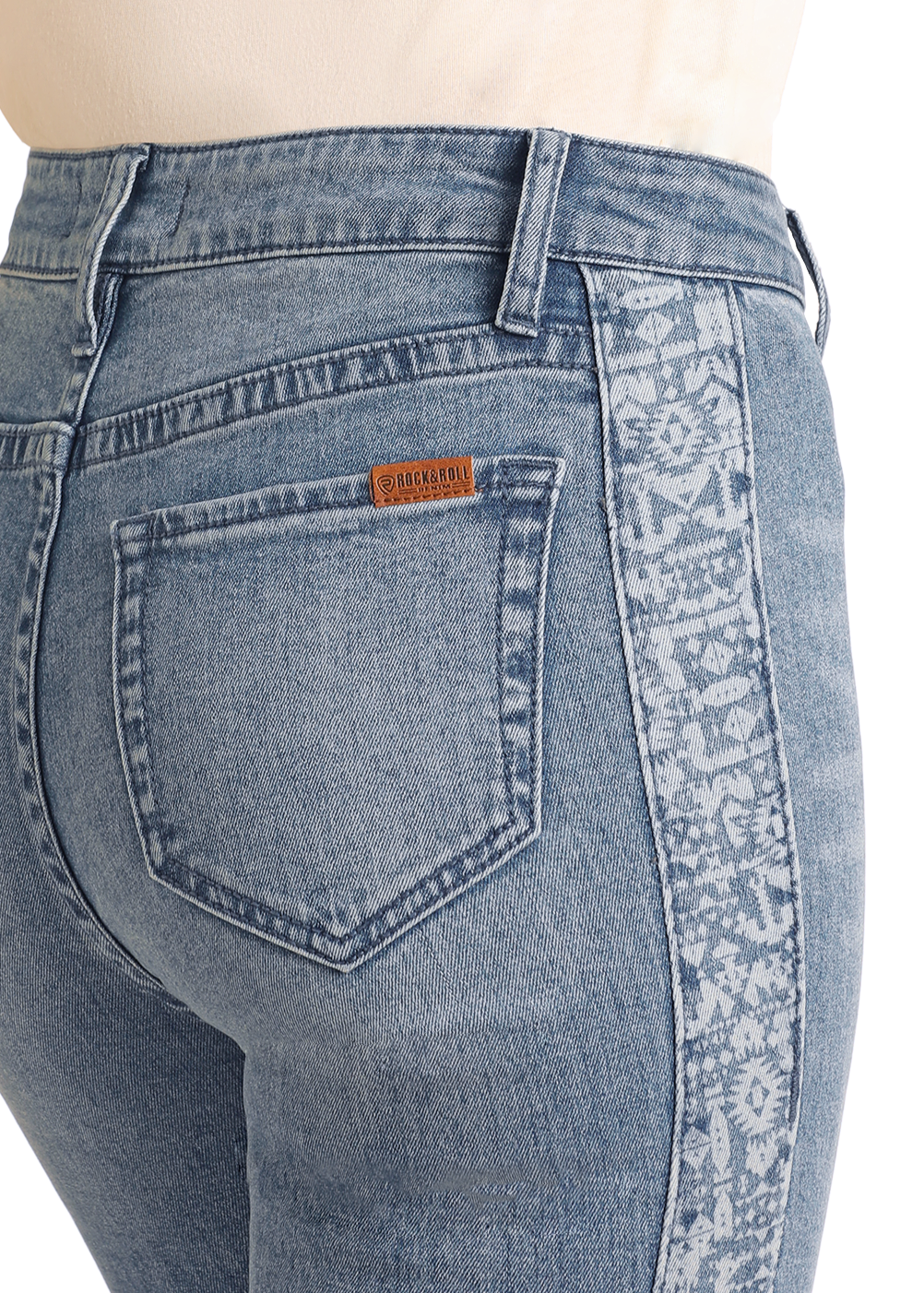 A close-up of the back and side of a person wearing Rock & Roll Denim Aztec Panel Button Flare Jeans, featuring a brown leather patch and a patterned light-colored stripe down the outer seam.
