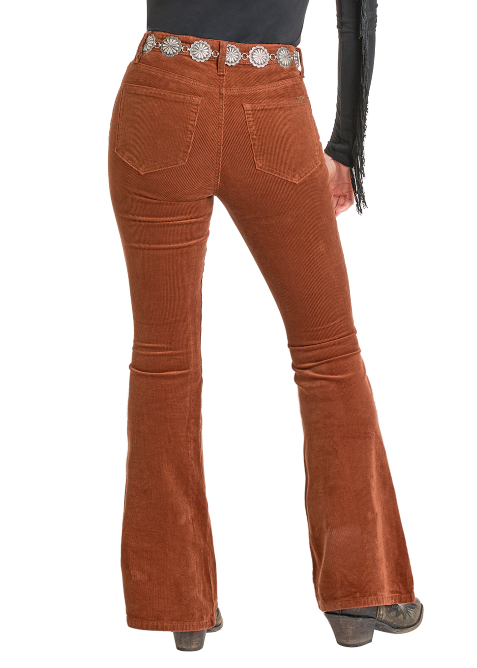 A person models Rock & Roll Denim's Rust Corduroy Flare Jeans, styled with a silver concho belt and black heeled boots, standing back to the camera against a white background.