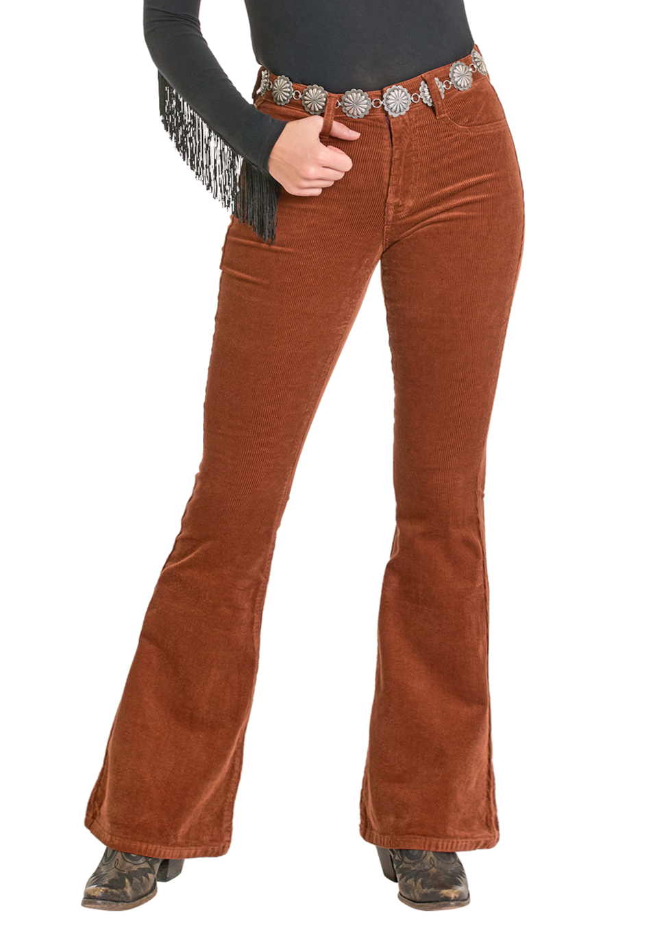 A person wearing Rust Corduroy Flare Jeans by Rock & Roll Denim, paired with a black fringe long-sleeve top, silver concho belt, and black boots, stands against a white background.