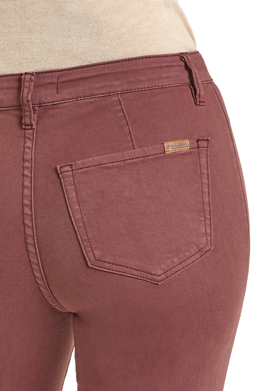 Close-up of a person wearing Rock & Roll Denim High Rise Wine Button Flare Jeans, featuring a back pocket with a leather brand label. The jeans are paired with a beige top; only the lower upper body is visible.