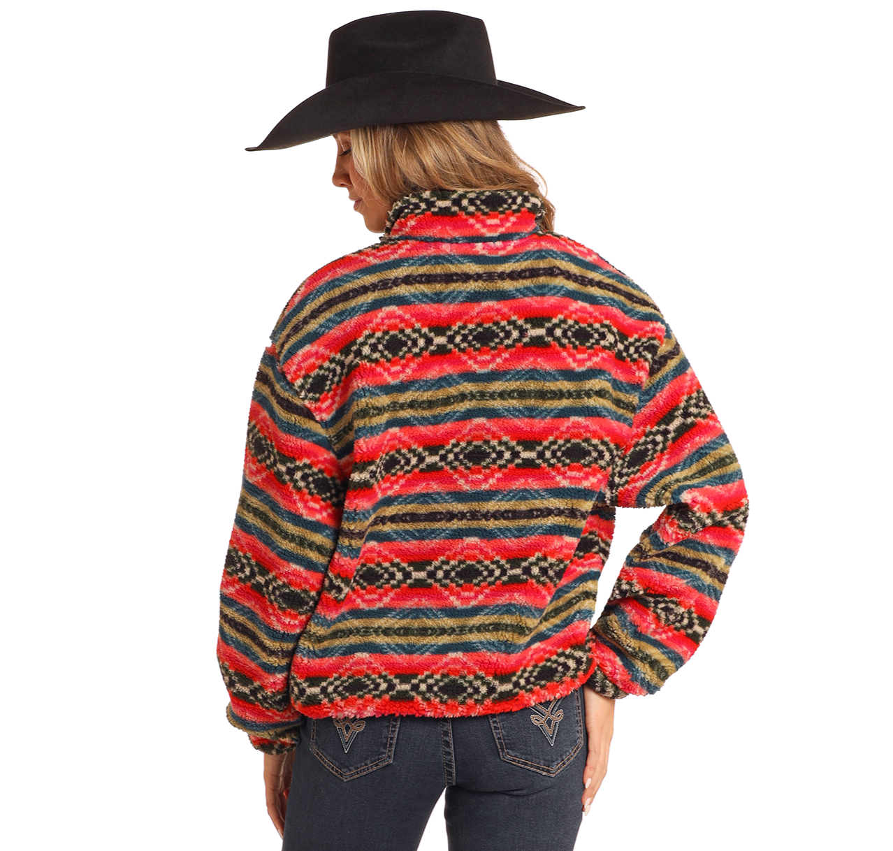 A person in the Rock & Roll Denim Striped Aztec Sherpa Pullover, featuring red, green, yellow, and black stripes, stands with their back to the camera wearing a black cowboy hat and dark blue jeans with decorative stitching.