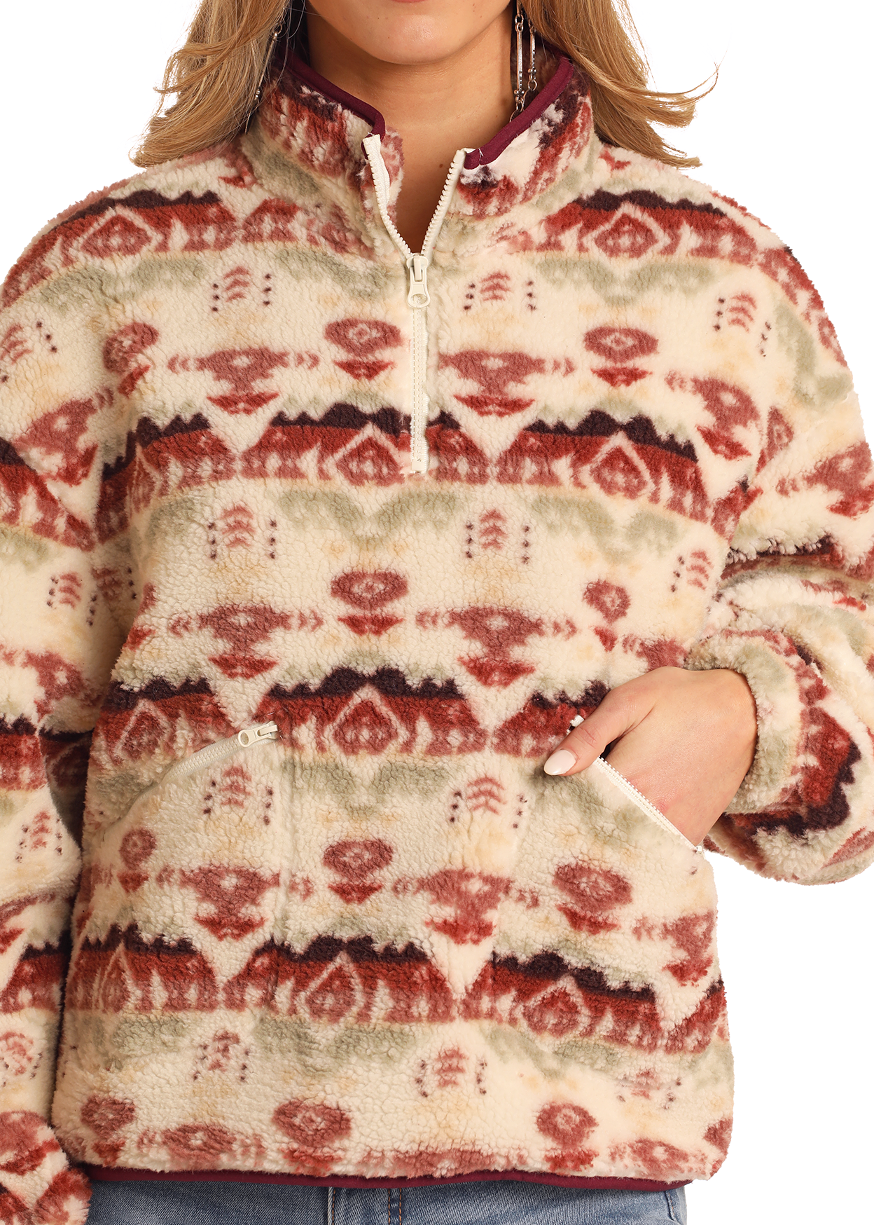 A person, face unseen, wears the Rock & Roll Denim Aztec Print Sherpa Pullover featuring a quarter zip front, large pocket, and red, beige, and green geometric patterns.