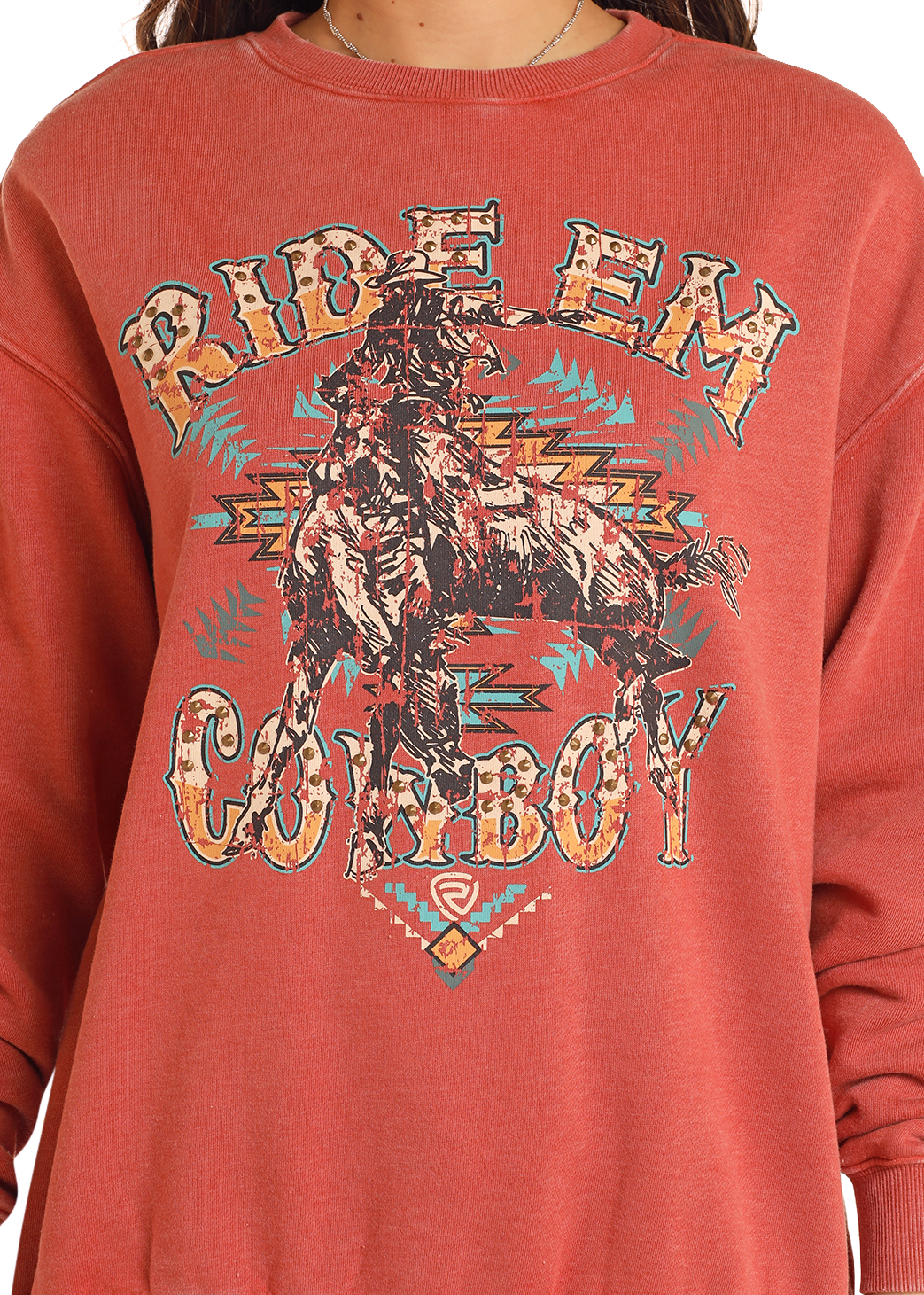 A person wearing the Rock & Roll Denim Studded Ride 'Em Cowboy Oversized Pullover, featuring a colorful studded cowboy-on-horse graphic and bold distressed "RIDE EM COWBOY" text.