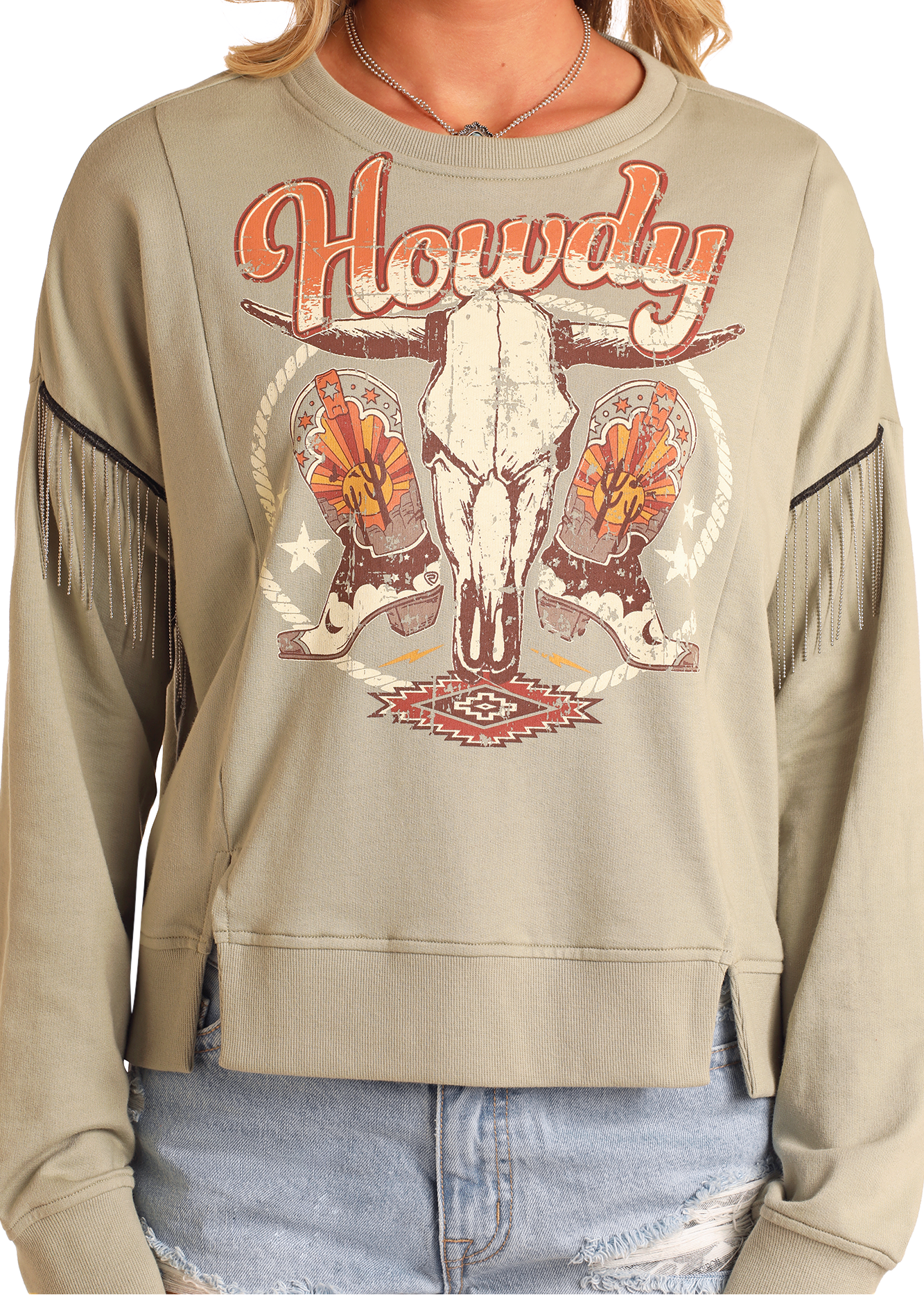 A person wears the Rock & Roll Denim Chain Fringe Howdy Graphic Pullover, featuring chain fringe sleeves and bold Western graphics, paired with ripped denim shorts for a relaxed, edgy look.