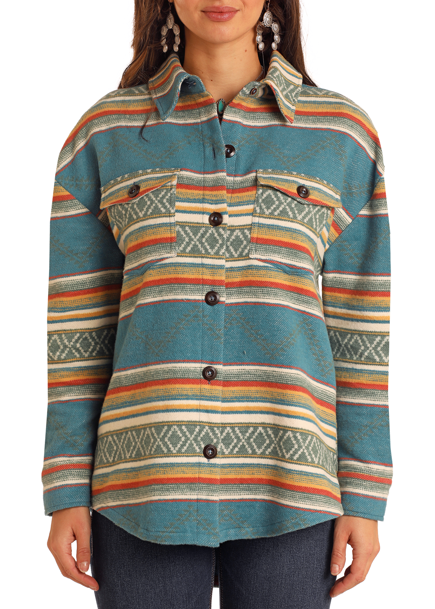 A woman layers the Rock & Roll Denim Turquoise Aztec Shacket—featuring horizontal multicolored stripes, geometric patterns, chest pockets, and dark buttons—with dark jeans for a casual look.