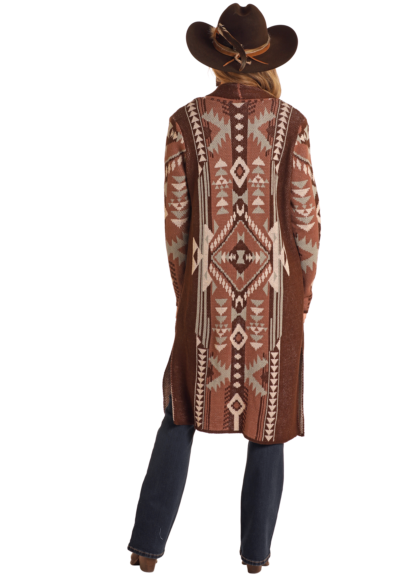 A person faces away from the camera, wearing a Rock & Roll Denim Brown Aztec Duster with earth-toned geometric designs, paired with a brown cowboy hat, blue jeans, and brown boots against a white background.