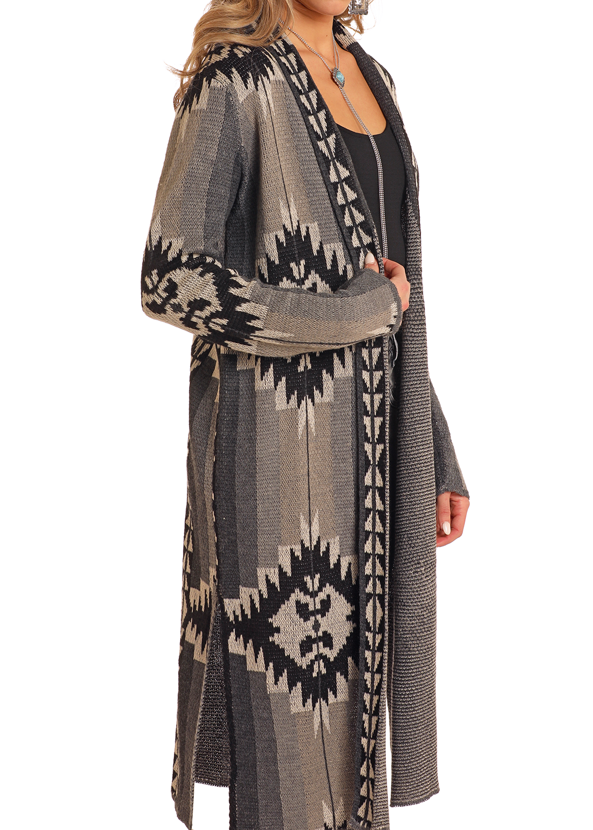 A person models the Rock & Roll Denim Charcoal Aztec Duster, a long-sleeve cardigan with black, gray, and beige geometric patterns over a black top—an ideal statement piece shown from shoulders to knees.