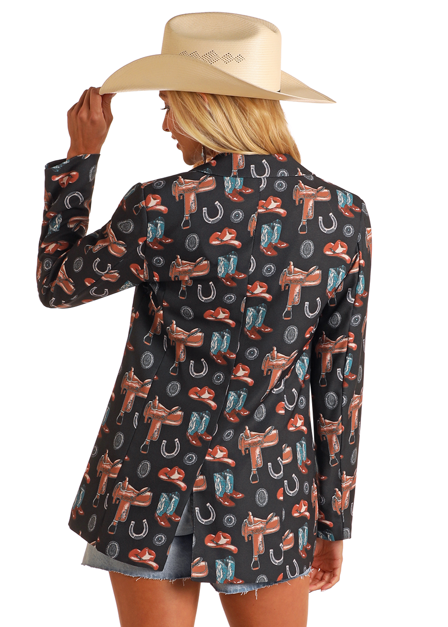 A woman faces away, wearing the Rock & Roll Denim Western Print Blazer with matching shorts and a beige cowboy hat, touching the hat brim with one hand.