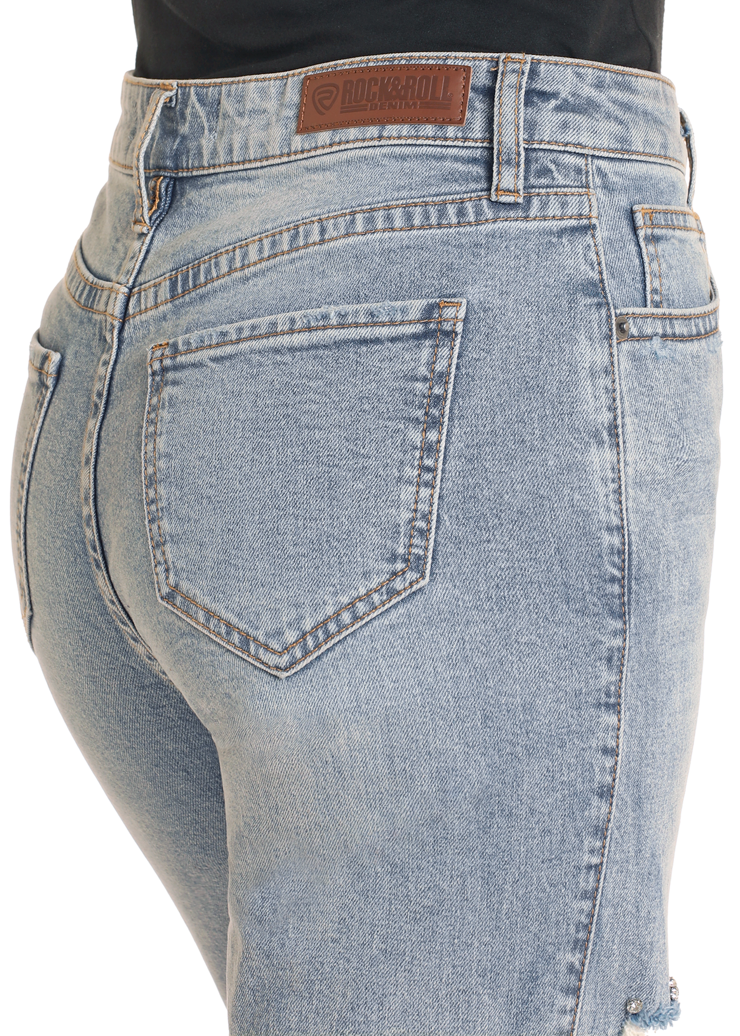 Close-up of the back of a person wearing Rock & Roll Denim High Rise Studded Straight Cropped Jeans, featuring light wash, visible back pocket, brown stitching, and a leather patch on the waistband.
