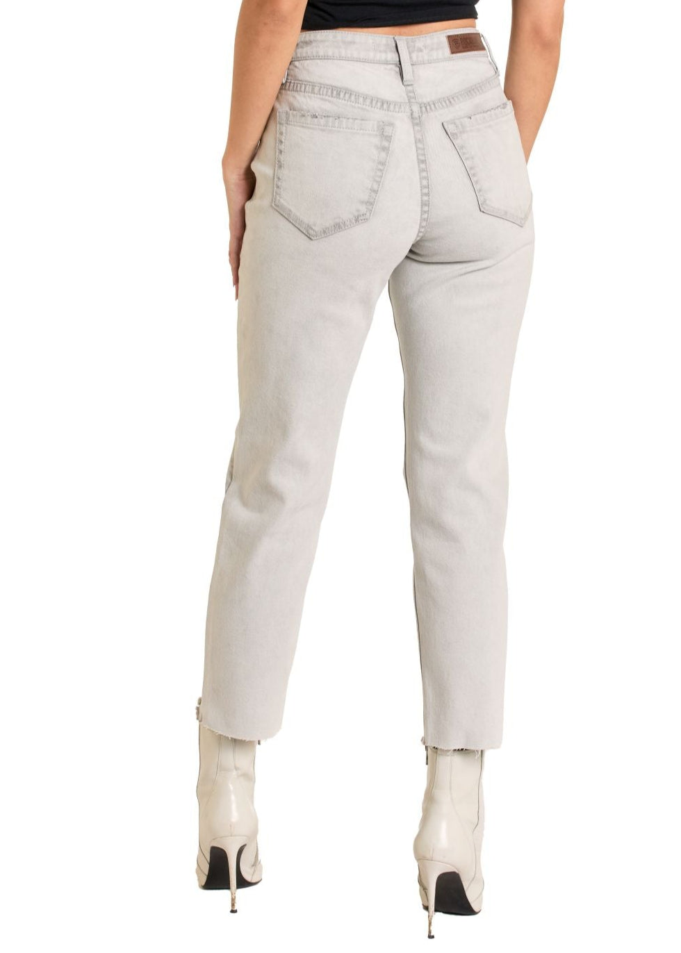 Woman wearing light gray jeans and a black top on a white background