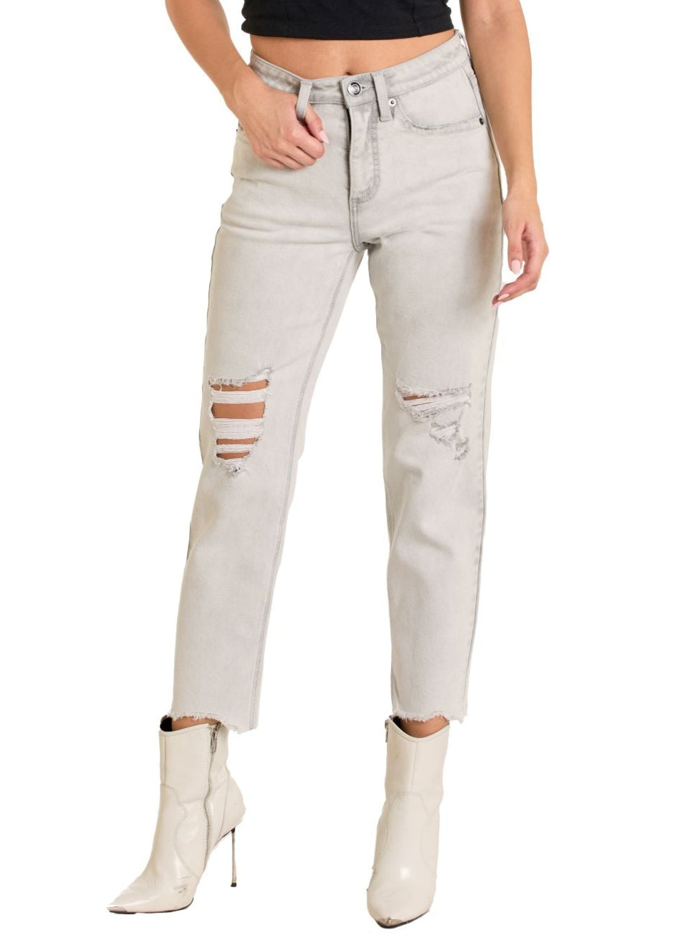 Woman wearing a black crop top and light gray ripped jeans on a white background