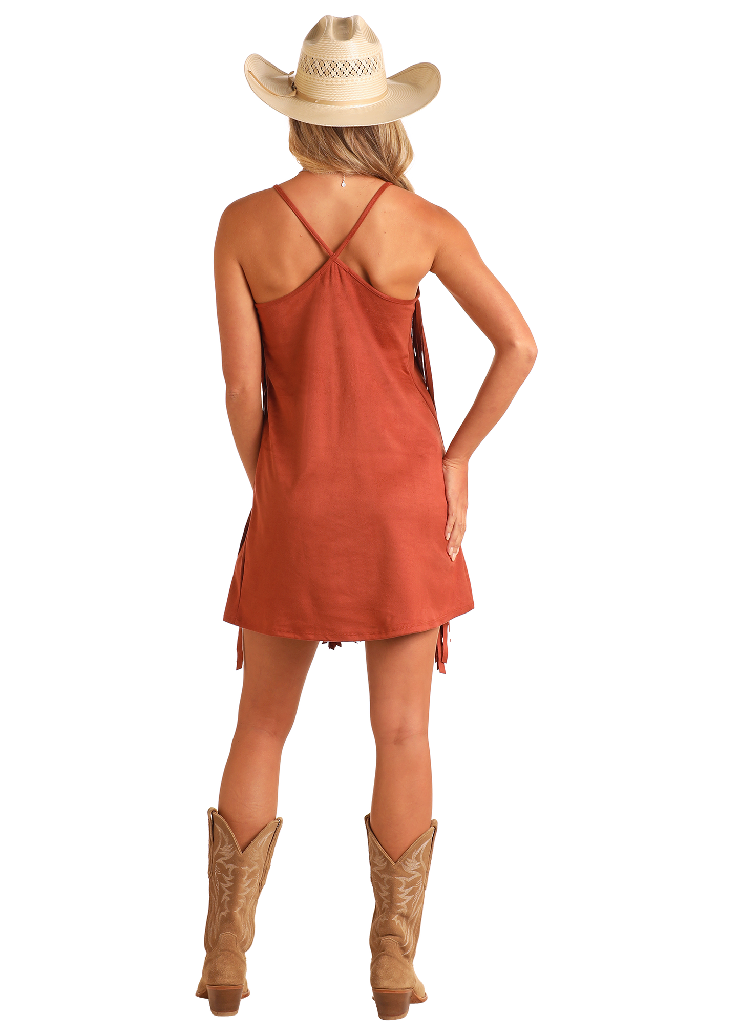 A woman stands facing away with one hand on her hip, showing the back of the Rock & Roll Denim Microsuede Fringe Dress, styled with a straw cowboy hat and tan boots.
