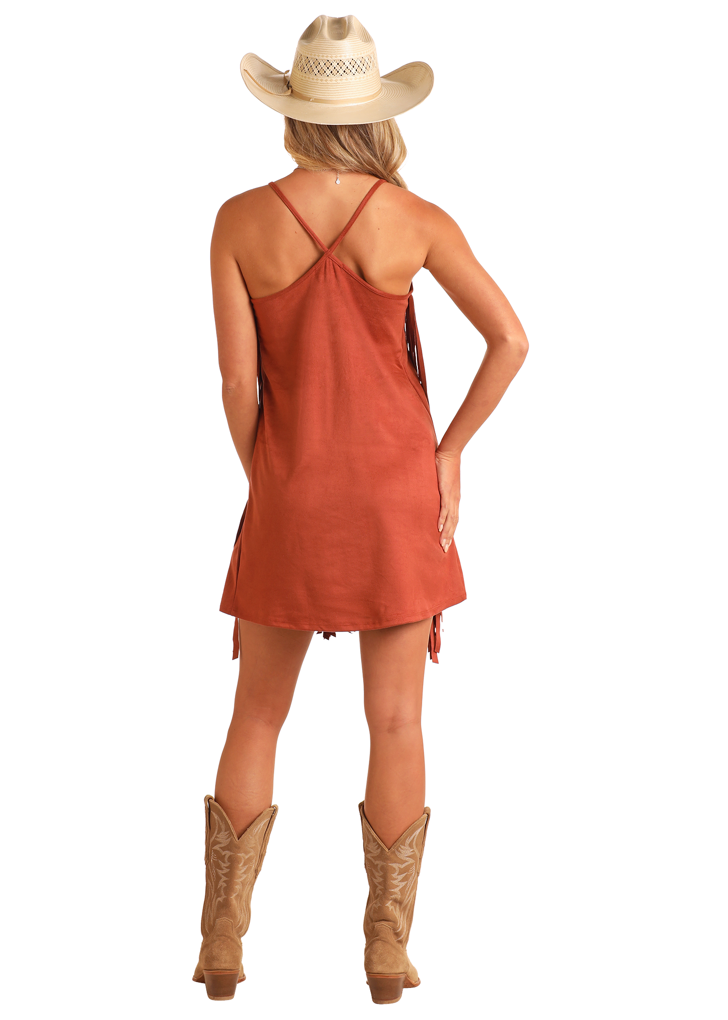 A woman stands facing away with one hand on her hip, showing the back of the Rock & Roll Denim Microsuede Fringe Dress, styled with a straw cowboy hat and tan boots.