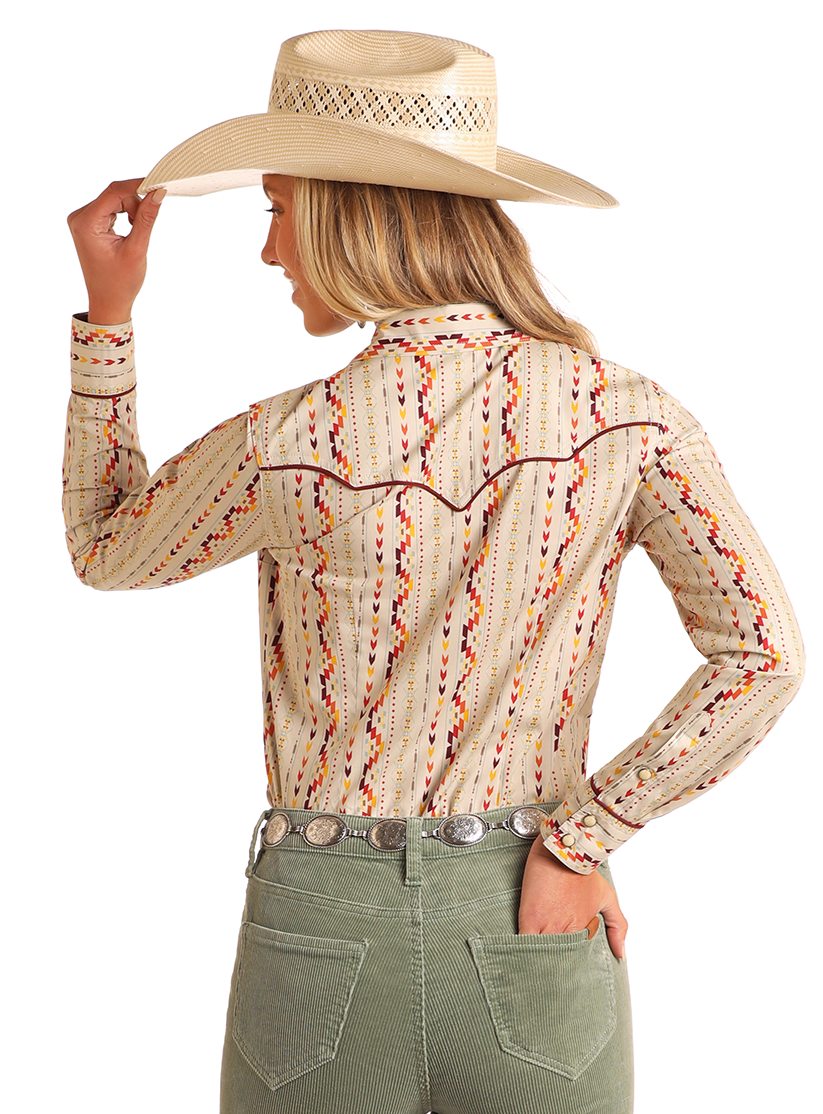 A person in a straw cowboy hat, green pants with a silver belt, and the Rock & Roll Denim Aztec Striped Long Sleeve Snap Shirt stands facing away, one hand on their hat brim.