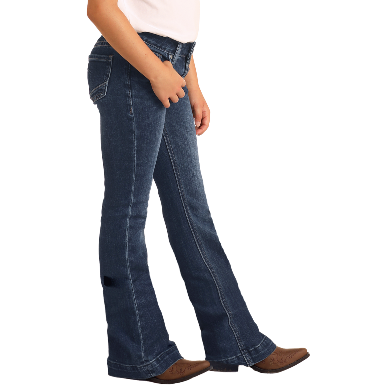 A person wearing Rock & Roll Denim Girls' Extra Stretch Mid Rise Trouser Jeans, a white shirt, and brown cowboy boots stands against a plain white background.