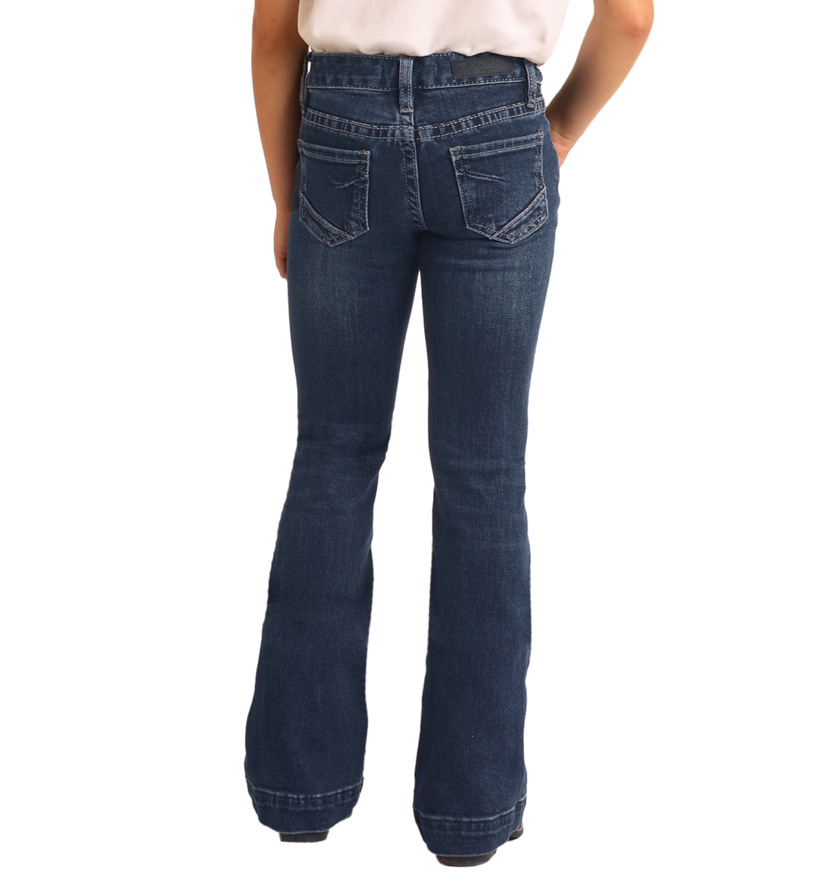 A girl is seen from behind wearing Rock & Roll Denim Girls' Extra Stretch Mid Rise Trouser Jeans with her hands in the back pockets, photographed against a white background.