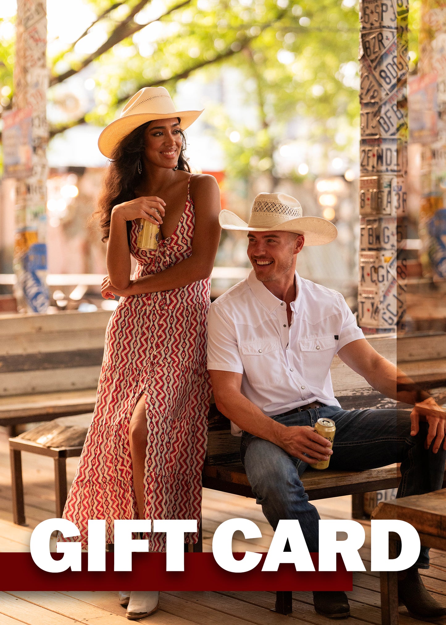 A woman in a patterned dress and a man in Rock & Roll Denim jeans and cowboy hats relax on a porch with drinks. Sunlight filters through the trees. Text: “Rock & Roll Denim E-Gift Card.”.