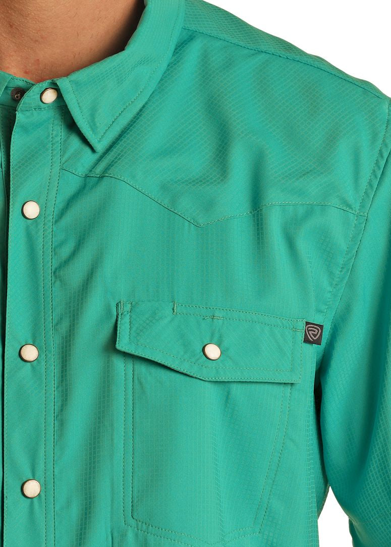 Close-up of a teal shirt with a pocket and button details on a white background