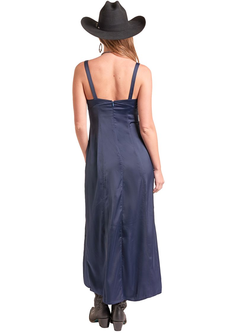A woman shown from the back wearing a navy blue satin slip dress with thin straps, a black cowboy hat, and dark boots against a plain white background.
