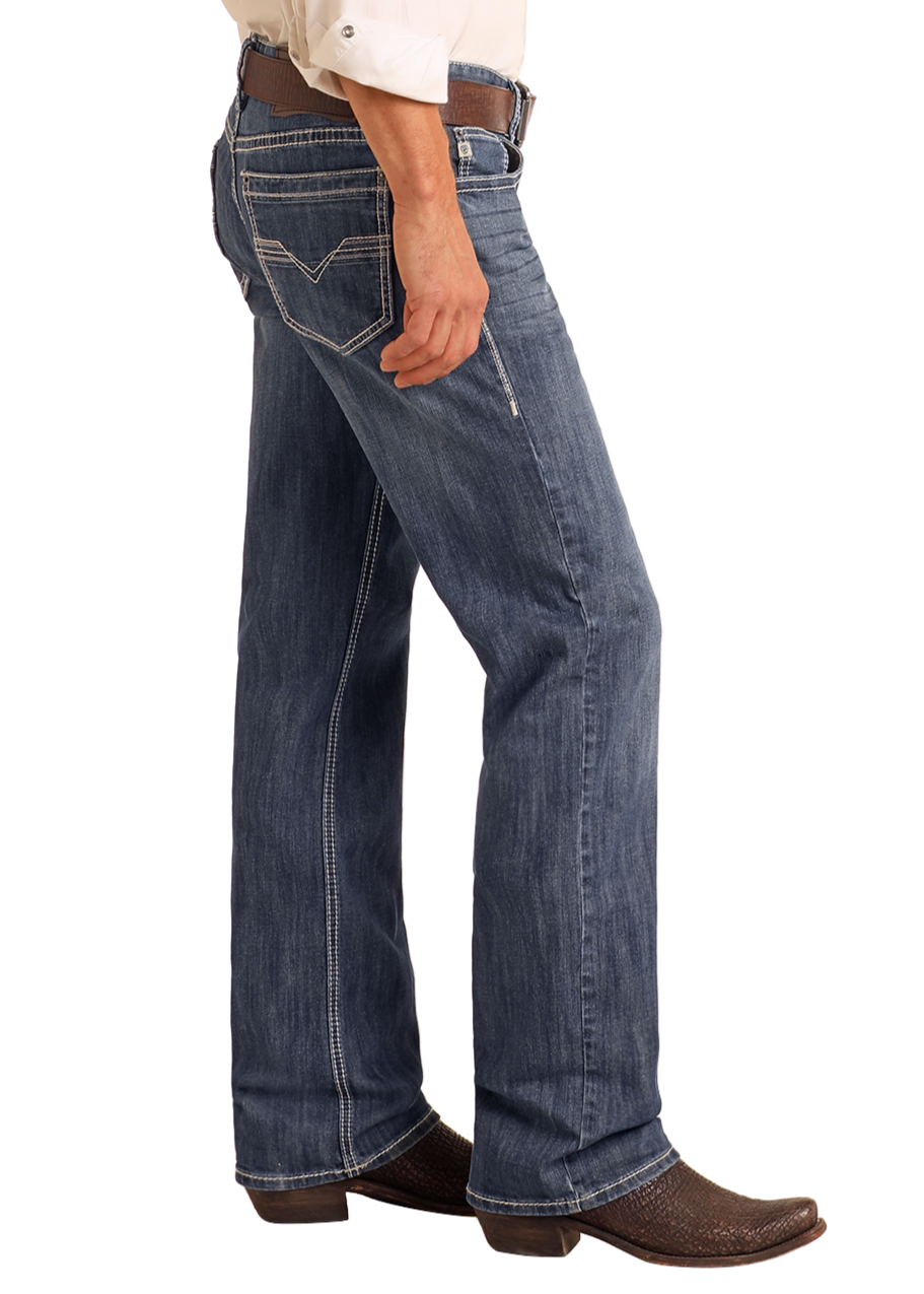 A person models Rock & Roll Denim Relaxed Fit Straight Leg Jeans in a vintage wash, styled with a brown belt and textured cowboy boots. Only the lower torso and legs are shown, hands in pockets, standing sideways.