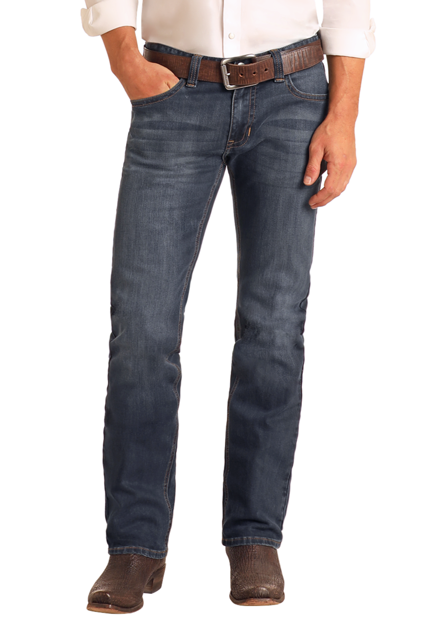Someone wearing Rock & Roll Denim Slim Fit Dark Wash Straight Leg Jeans, a brown belt, white shirt, and brown boots stands with one hand in their pocket against a plain white background.