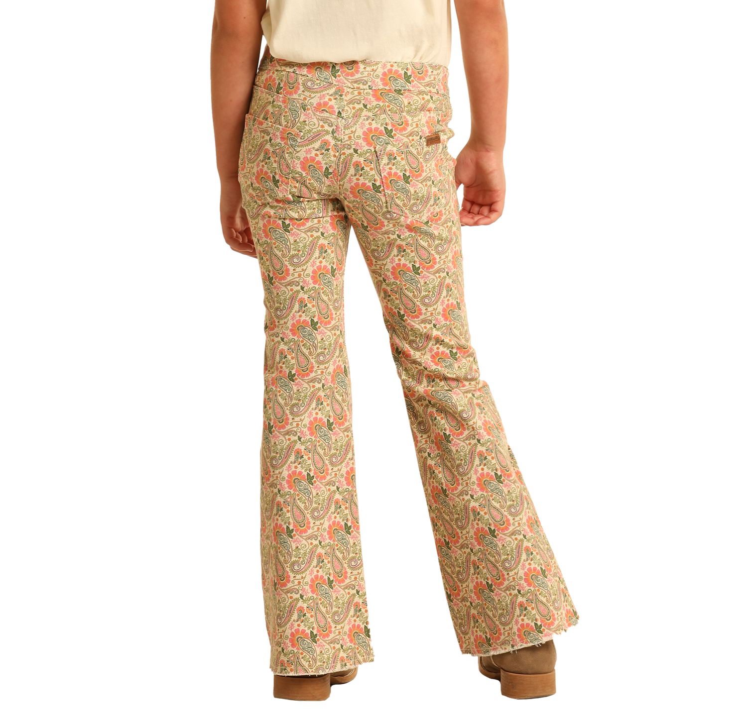 A girl is seen from behind wearing Rock & Roll Denim Girls' Paisley Print Flare Jeans with a beige top and brown platform shoes, against a plain white background.