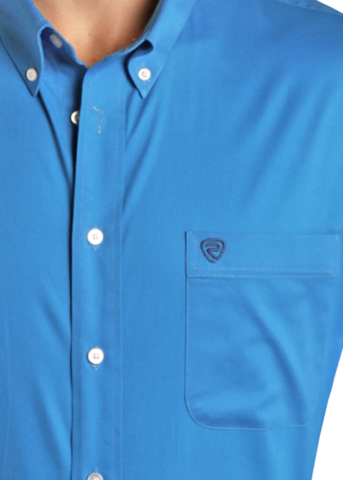 A person wears the Rock & Roll Denim Regular Fit Blue Long Sleeve Button Shirt with a chest pocket, paired with light-wash jeans and a black belt. Their left hand is in their pocket, and their head is out of frame.