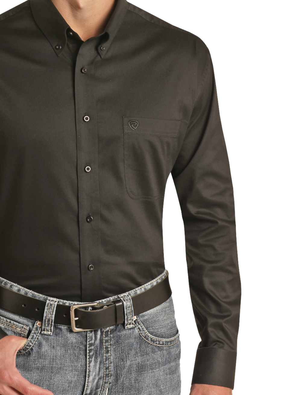 A person wears a Rock & Roll Denim Regular Fit Black Long Sleeve Button Shirt with a front pocket, paired with faded blue jeans and a black leather belt. Their left hand is tucked into the jeans’ front pocket.