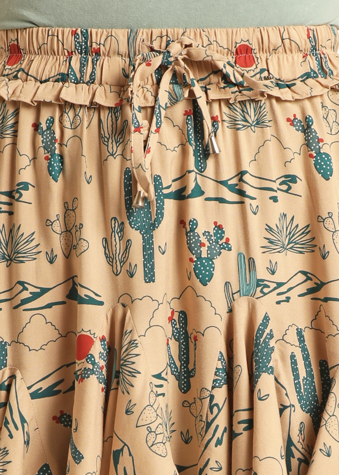 Close-up of the Rock & Roll Denim Desert Godet Skirt, featuring a ruffled tie-front elastic waist, green cacti and red flower desert print, and delicate godet pleats that add stylish movement to this unique design.