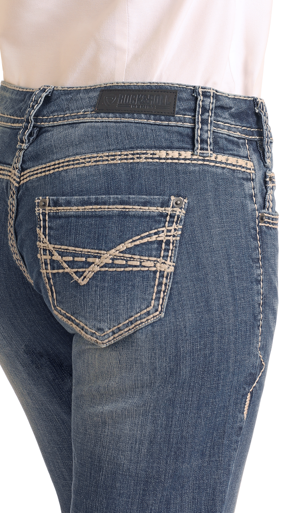 A close-up of a person wearing Rock & Roll Denim Mid Rise Bootcut Riding Jeans with decorative white stitching on the back pocket and waistband, styled with a tucked-in white shirt.
