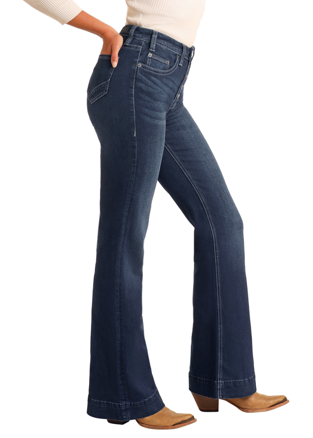 A person poses sideways against a plain background wearing Rock & Roll Denim's Button Fly High Rise Trousers in dark blue, styled with a white top and tan heeled boots.