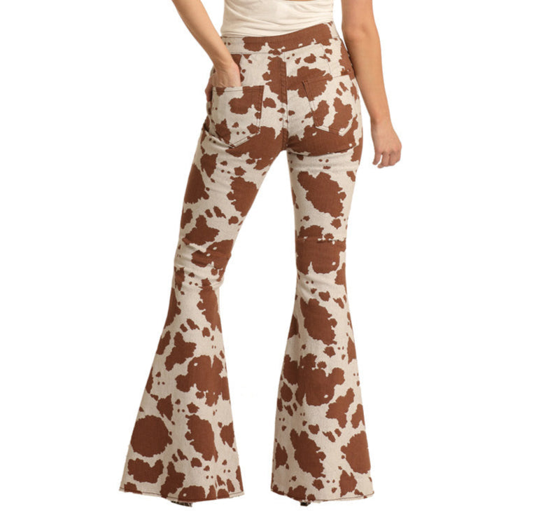 A person seen from the back wears Rock & Roll Denim's Cow Print Button Bells—high-rise bell bottom jeans featuring a brown and white cow print, offering a modern update to classic Western style.