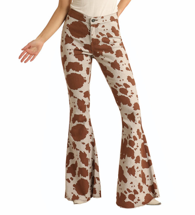 Wearing Rock & Roll Denim’s Cow Print Button Bells, this person showcases iconic Western flair in brown and white high-rise bell bottom jeans. Their pose highlights only their torso and legs, with one hand raised and the other relaxed.