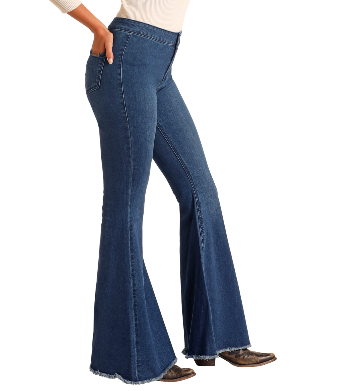 A person wears Rock & Roll Denim Dark Wash High Rise Bell Bottoms, styled with brown pointed-toe boots and a cream long-sleeve top, standing against a plain light background.
