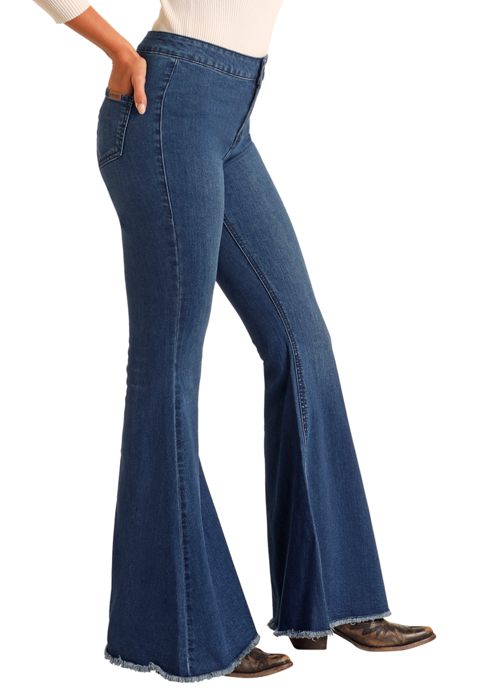 A person wears Rock & Roll Denim Dark Wash High Rise Bell Bottoms, styled with brown pointed-toe boots and a cream long-sleeve top, standing against a plain light background.