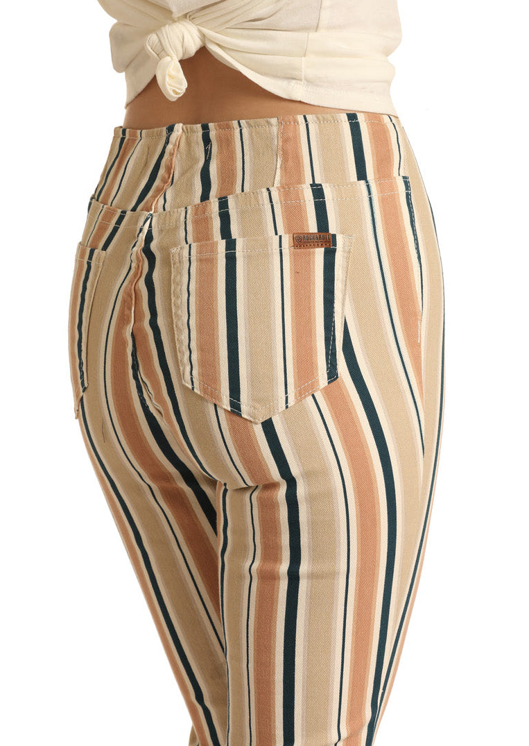 A person wears Rock & Roll Denim Striped High Rise Flare Leg Jeans in beige, black, and rust, paired with a white waist-tied top; the image is cropped to show only the lower torso and upper legs.