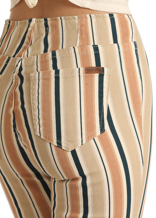 A person wears Rock & Roll Denim Striped High Rise Flare Leg Jeans in beige, black, and rust, paired with a white waist-tied top; the image is cropped to show only the lower torso and upper legs.