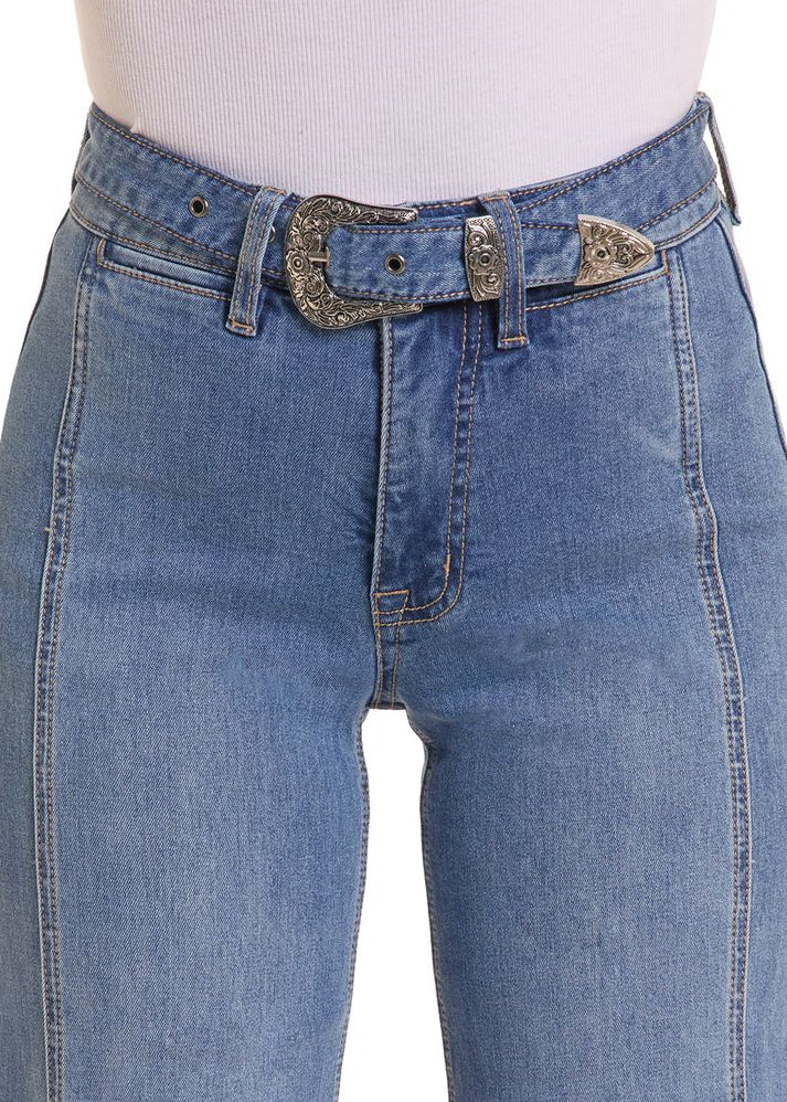 Close-up of a woman wearing blue denim jeans with a decorative silver western-style belt.