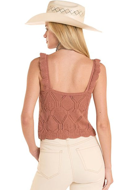 Woman wearing a brown sleeveless top and beige pants with a white background