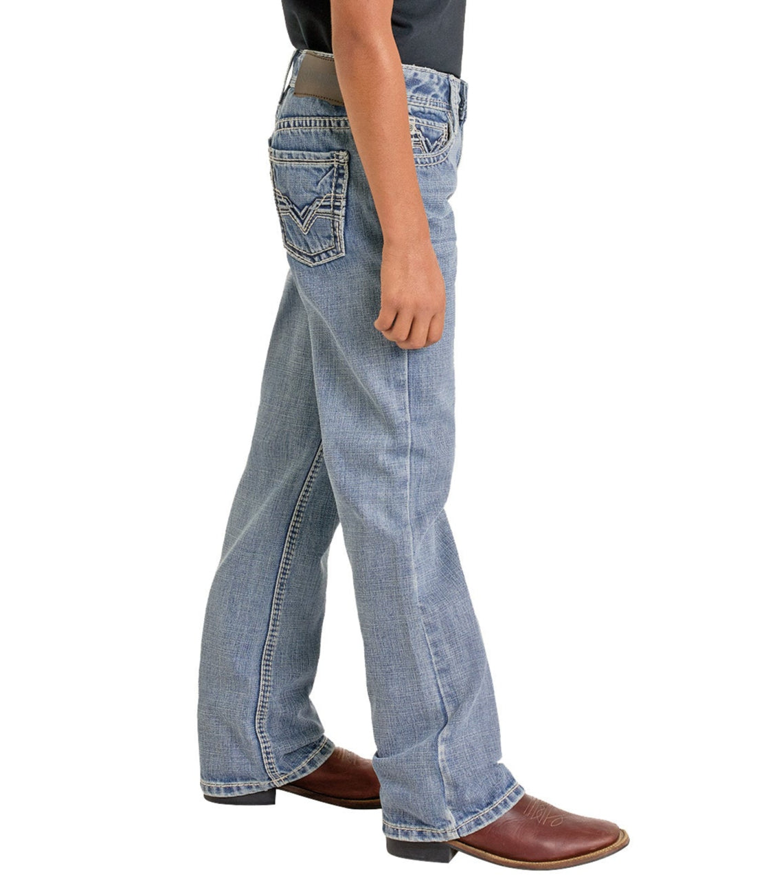 A boy wears Rock & Roll Denim Boys' Regular Fit Raised Signature Bootcut Jeans in light blue, paired with a black tucked-in shirt and brown leather boots, standing in profile against a white background.