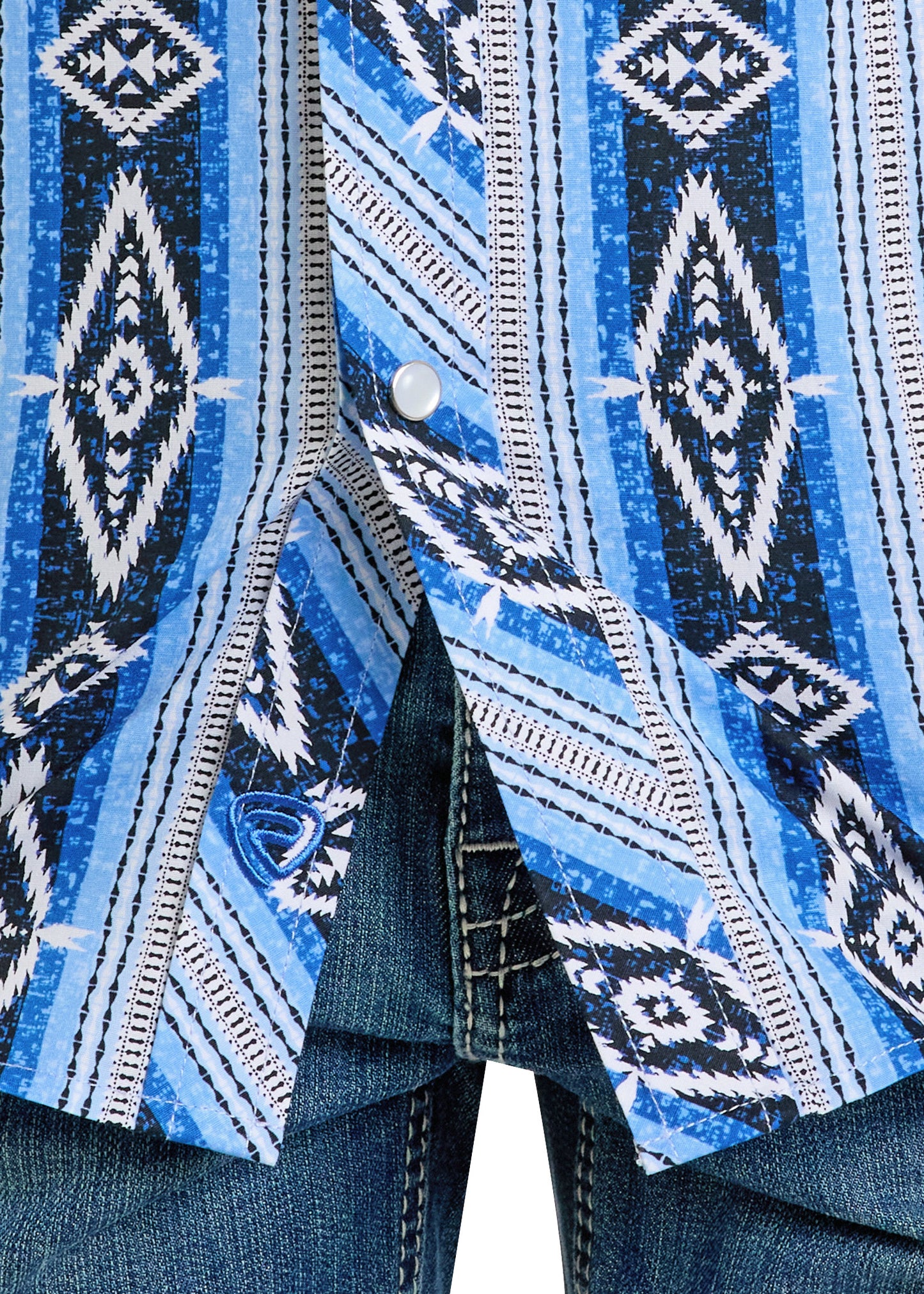 Close-up of the Boys' Blue Aztec Stripe Long Sleeve Snap Shirt by Rock & Roll Denim, slim fit with geometric designs, partially unbuttoned at the bottom and worn over blue denim jeans with white stitching.
