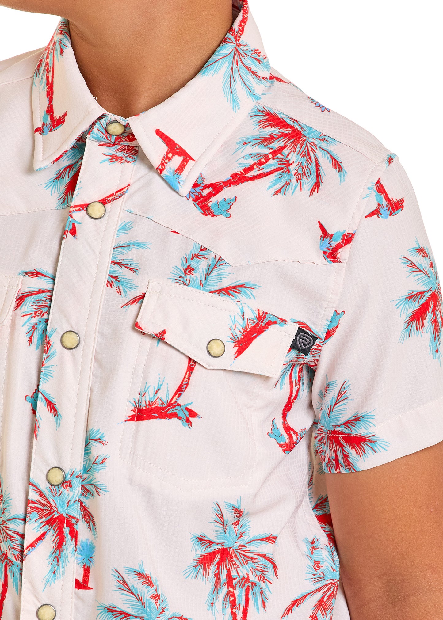 A person wearing a Rock & Roll Denim Boys' TEK Western Palm Tree Short Sleeve Shirt—a white button-up with red and blue palm tree print, snap buttons, and flap front pockets. Only the upper body is visible.