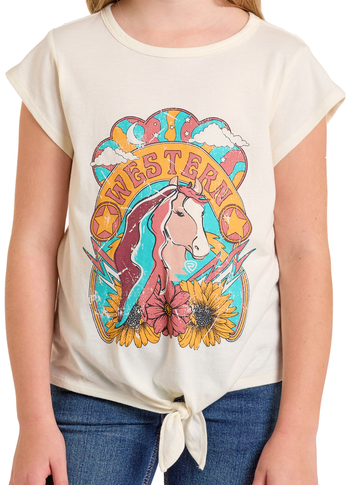 A child wears the Rock & Roll Denim Girls' Western Tie Front Graphic Tee, cream-colored with a unicorn, sunflowers, clouds, bold "WESTERN" lettering, and a knotted waist. Paired with blue jeans for a fun Western look.