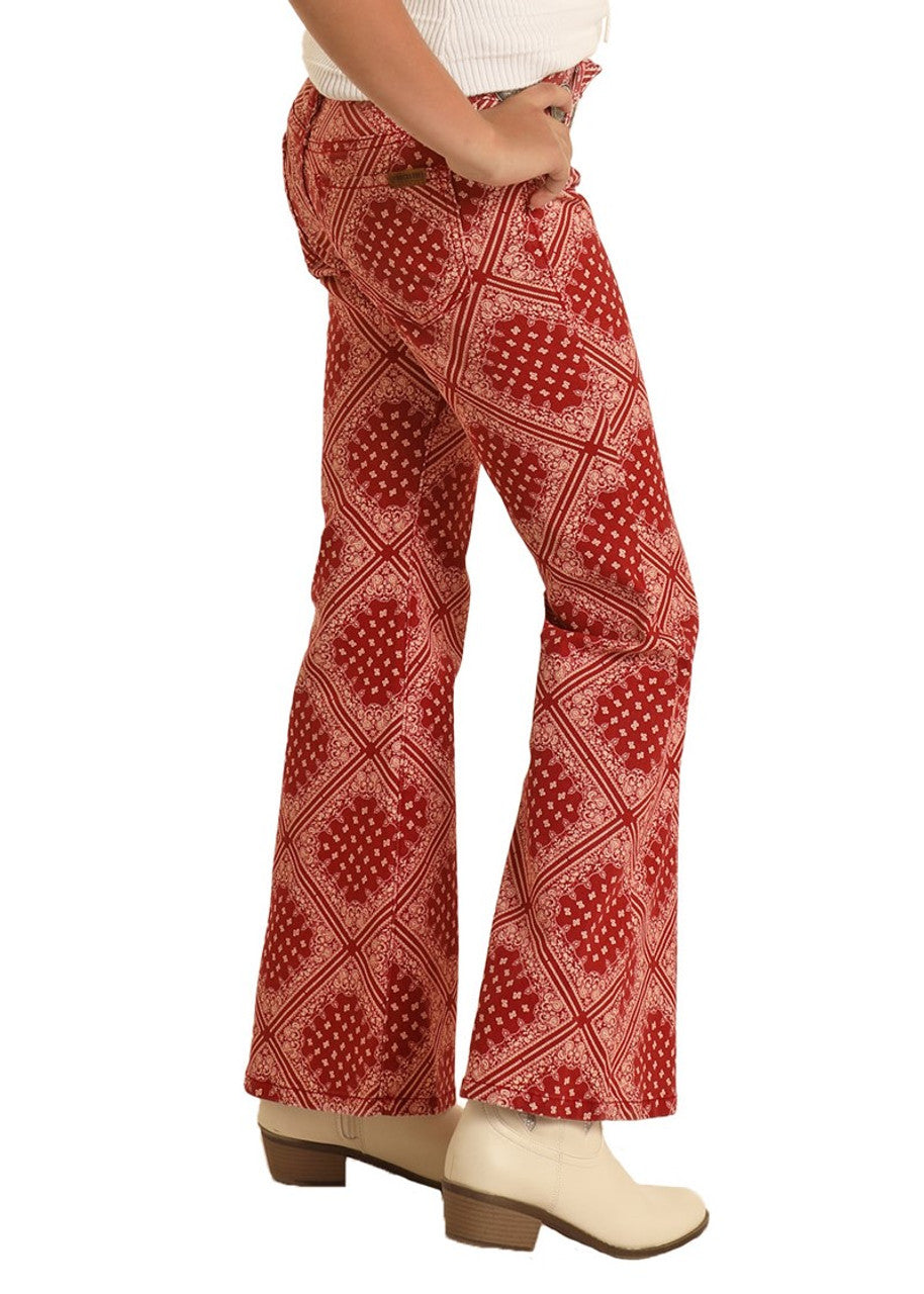 A girl models Rock & Roll Denim Girls' Bandana Print Flare Jeans, styled with white ankle boots and a confident pose, showcasing bold western flair.