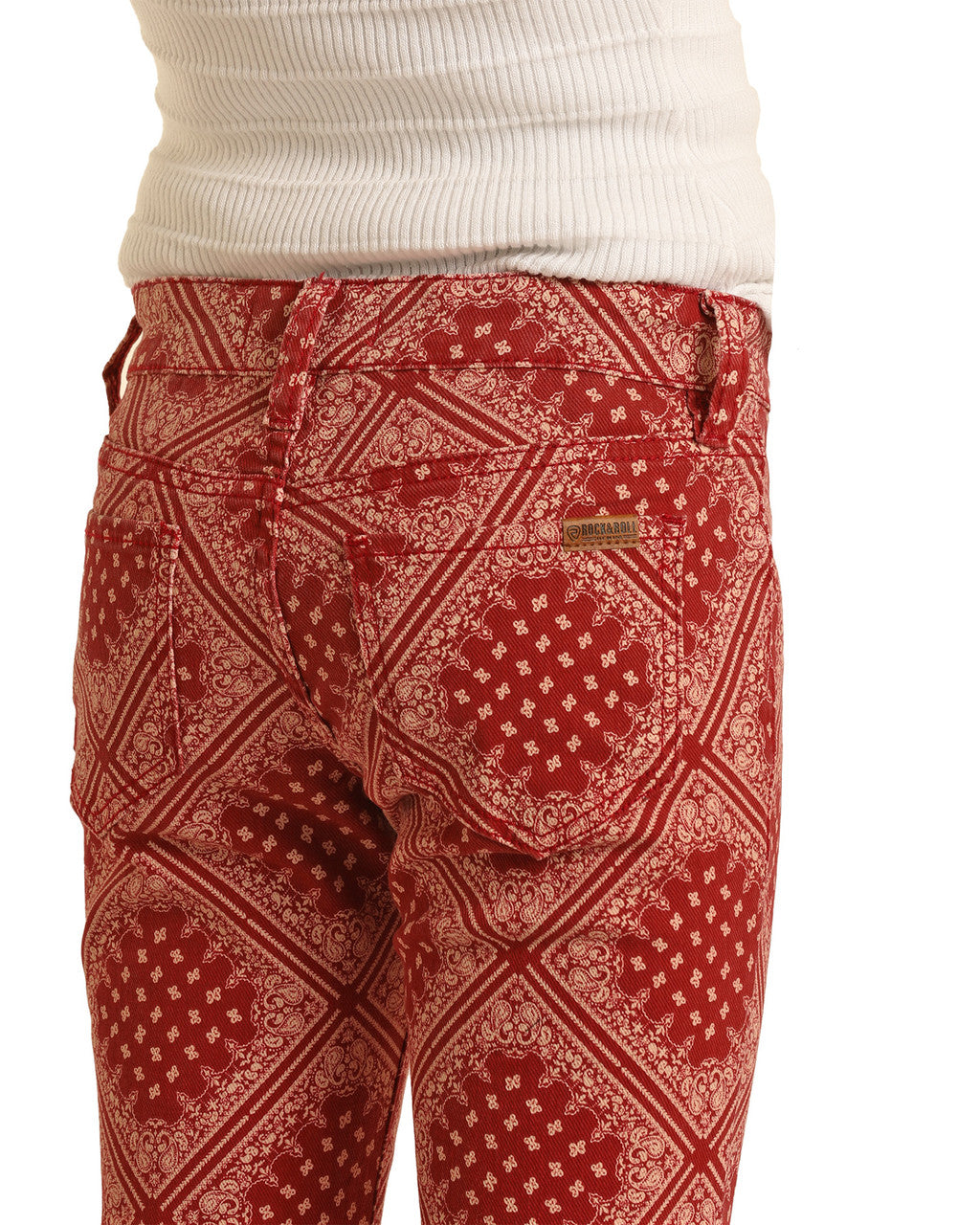 A person wearing Rock & Roll Denim Girls' Bandana Print Flare Jeans and a white ribbed top. The image focuses on the waist and upper thighs, showcasing the western-inspired bandana pattern and unique design.