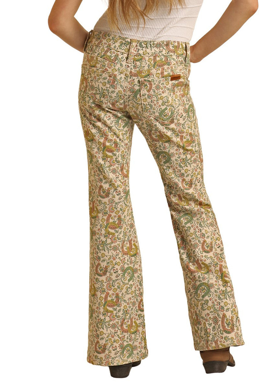 A girl stands facing away in Rock & Roll Denim Girls' Floral Horseshoe Print Flare Jeans and a white ribbed top, her long hair down her back and hands on hips.