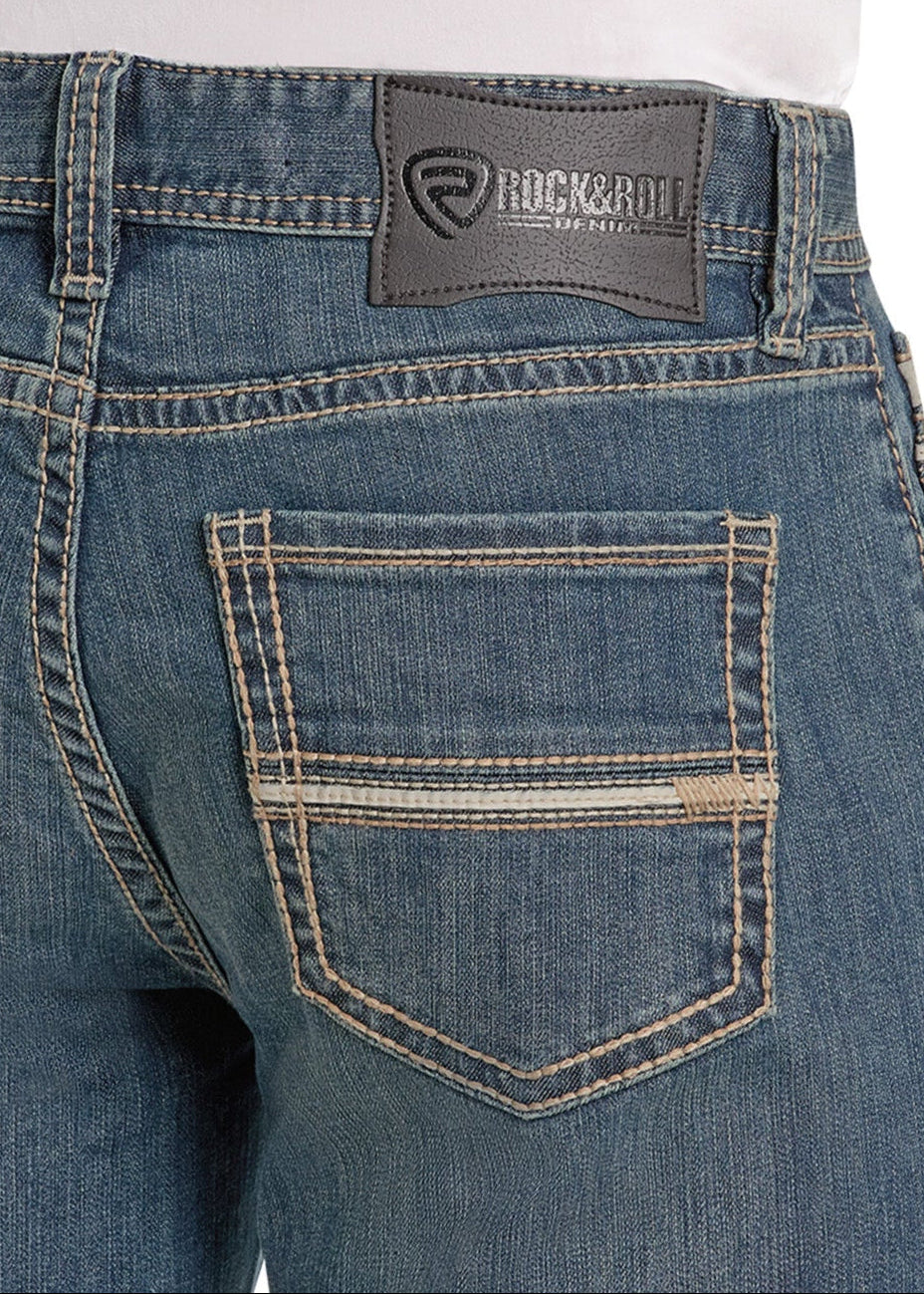 Close-up of the back pocket and waistband of blue Loose Fit Rope Stitch Tapered Bootcut Jeans by Rock & Roll Denim, featuring a black leather patch and worn by a person in a white shirt.