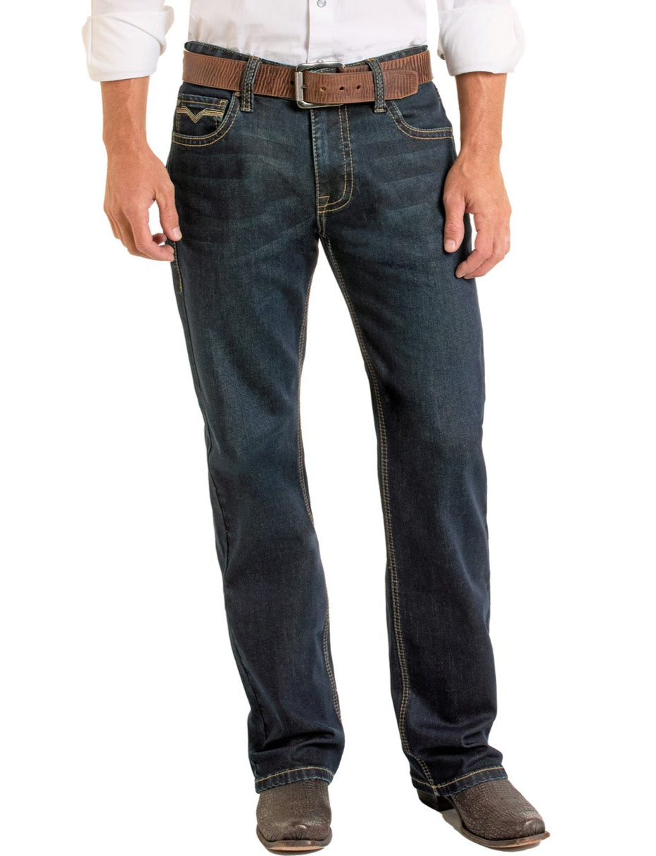 A person wearing Rock & Roll Denim Relaxed Fit Flat Seam Pocket Straight Leg Jeans, a brown belt, a white long-sleeve shirt with rolled-up sleeves, and brown cowboy boots stands against a white background.
