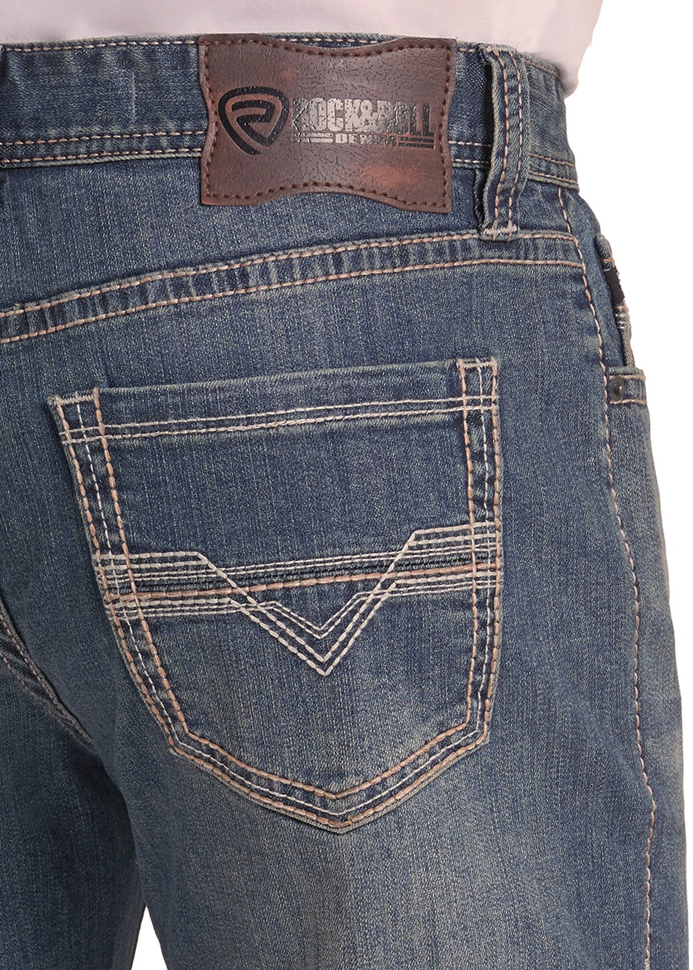 Close-up of the back waistband and pocket area of blue denim jeans, showing a brown Rockroll brand leather patch and contrast stitching.