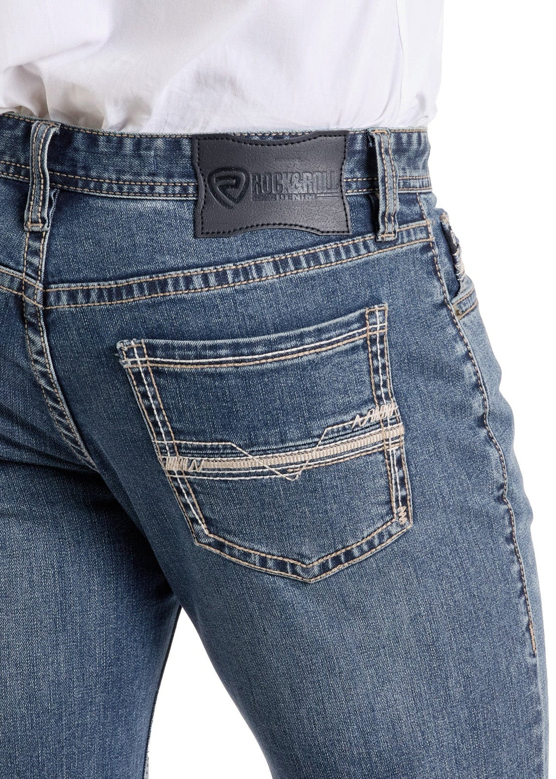A person wears Rock & Roll Denim Slim Fit Ladder Stitch Pocket Straight Leg Jeans in blue, featuring double-stitched pockets and a black brand label on the waistband. The tucked-in shirt reveals only the lower torso and upper legs.